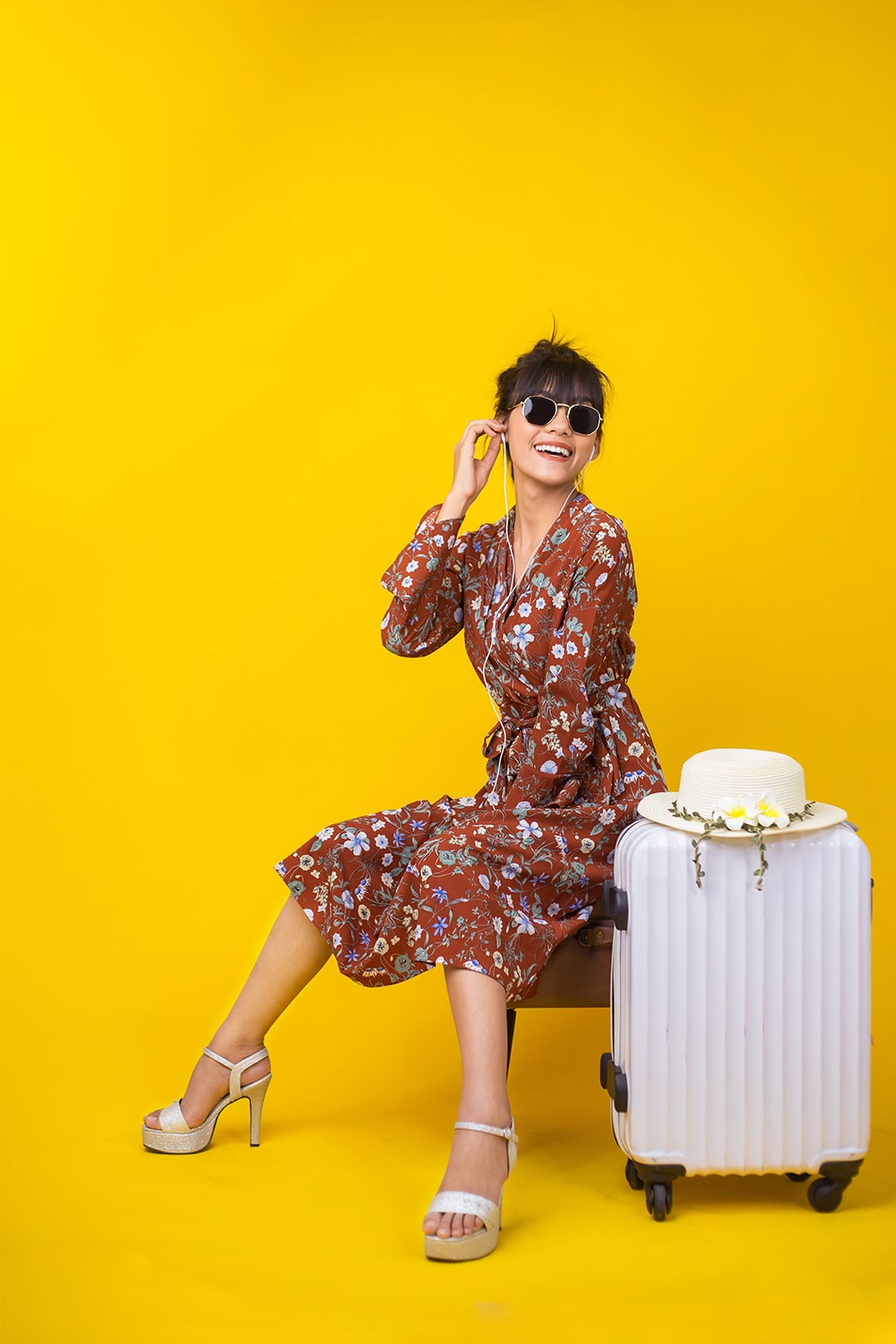 Young Asian  girl she is sit and smile happiness with luggage for travel in yellow background studio. Traveller on summer concept.