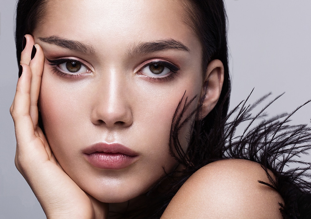 Close-up portrait of a beautiful fashion model in black with glossy makeup.