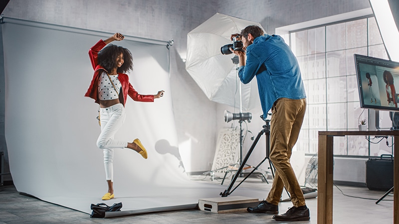 Behind,The,Scenes,On,Photo,Shoot:,Beautiful,Black,Model,Poses Behind the Scenes on Photo Shoot: Beautiful Black Model Poses for a Photographer, he Takes Photos with Professional Camera. Stylish Fashion Magazine Photoshoot done with Pro Equipment in a Studio
