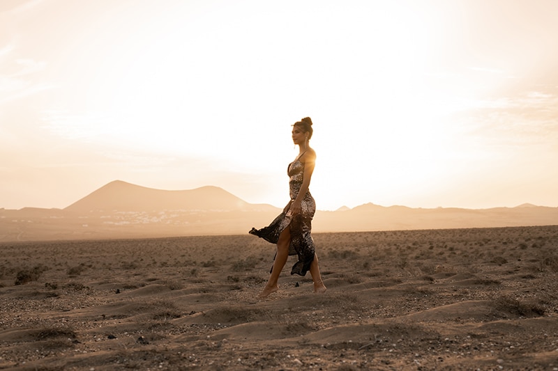 Fashion model in beautiful luxury gold dress during sunset golden hour in the desert