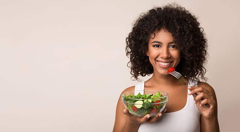 African-american,Woman,Eating,Vegetable,Salad,Over,Light,Background,With,Copy